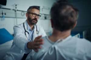 Doctor consoling a patient, with the patient wondering if their cancer is covered by FELA.