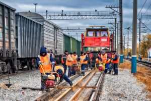 Railroad workers inspect freight railcars and review safety procedures in a busy railroad yard.
